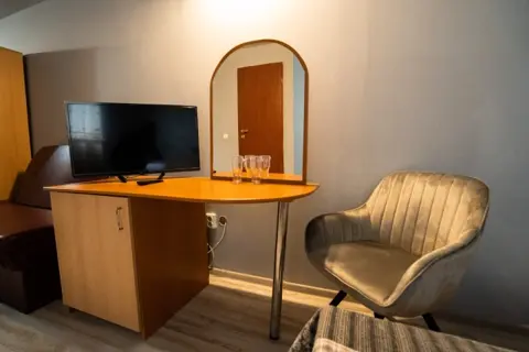 Colț de cameră cu birou, televizor și fotoliu