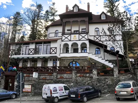 Fațada pensiunii din Sinaia, cu steaguri și balcoane din lemn