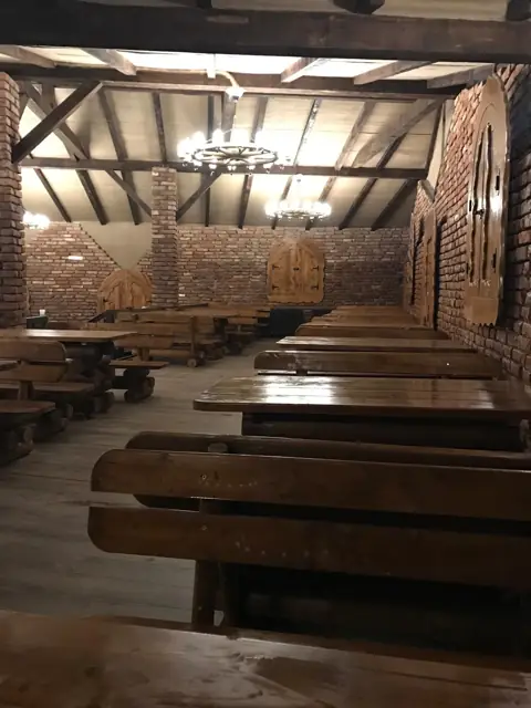 Sala mare văzută de la intrare, cu bănci de lemn