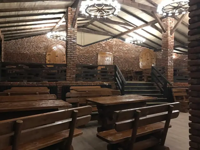 Sala din cărămidă, cu mese lungi și candelabre din roți de car