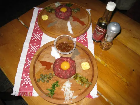 Biftec tartar, servit pe tocător de lemn