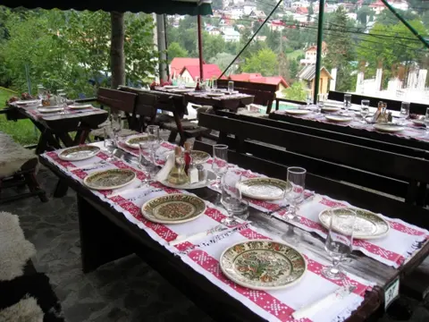 Terasa cu mese lungi de lemn și fețe de masă tradiționale