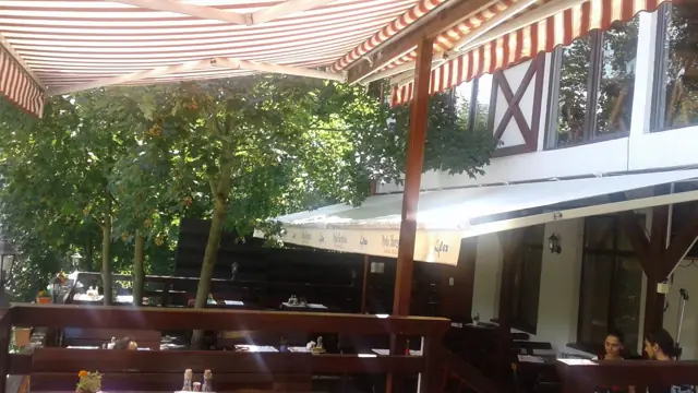 Terasa restaurantului, sub copertine, între copaci